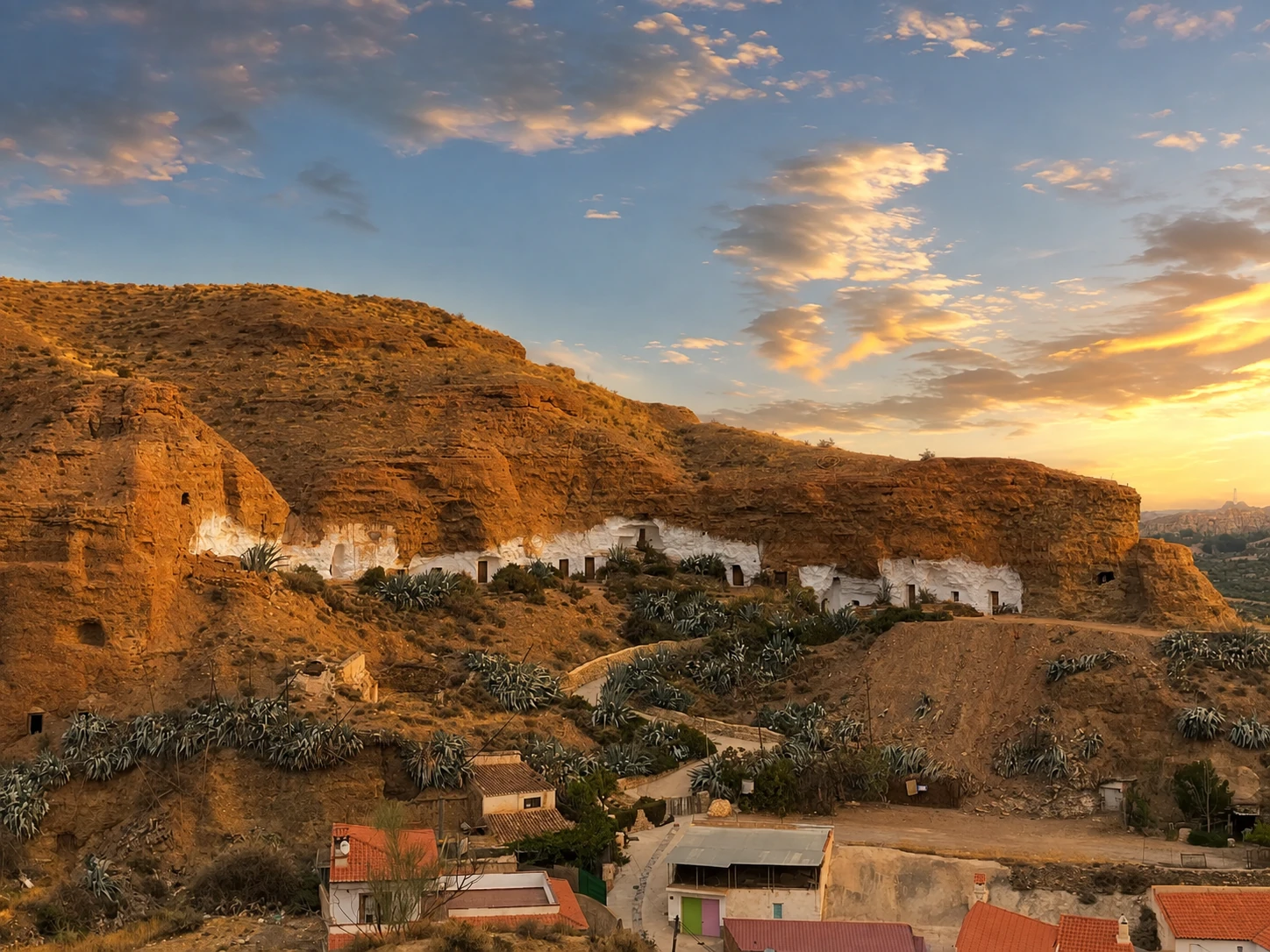 Casas cueva de Los Algarbes en la ladera al atardecer
