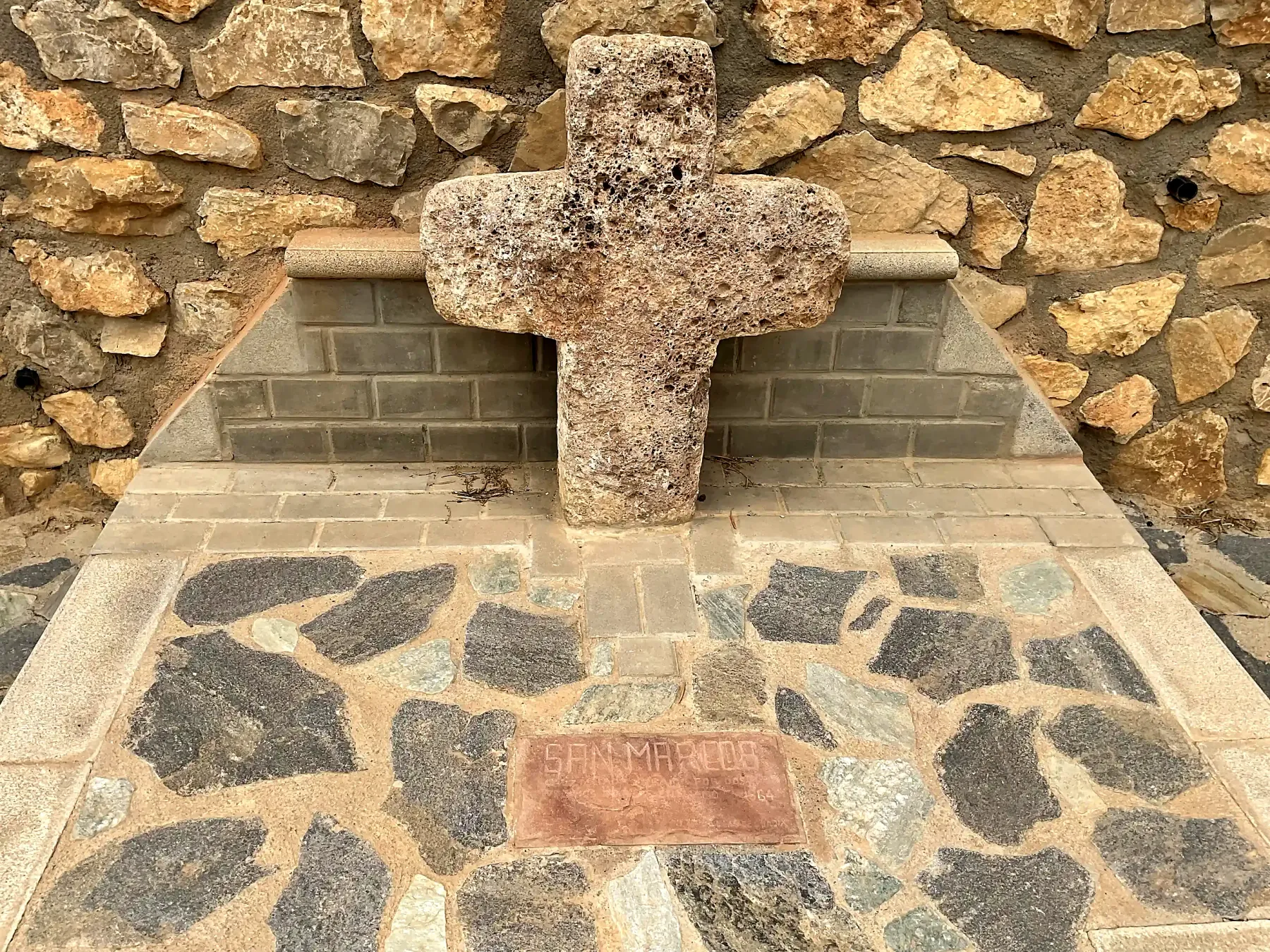 Detalle de la piedra porosa de la cruz y de la placa situada a sus pies