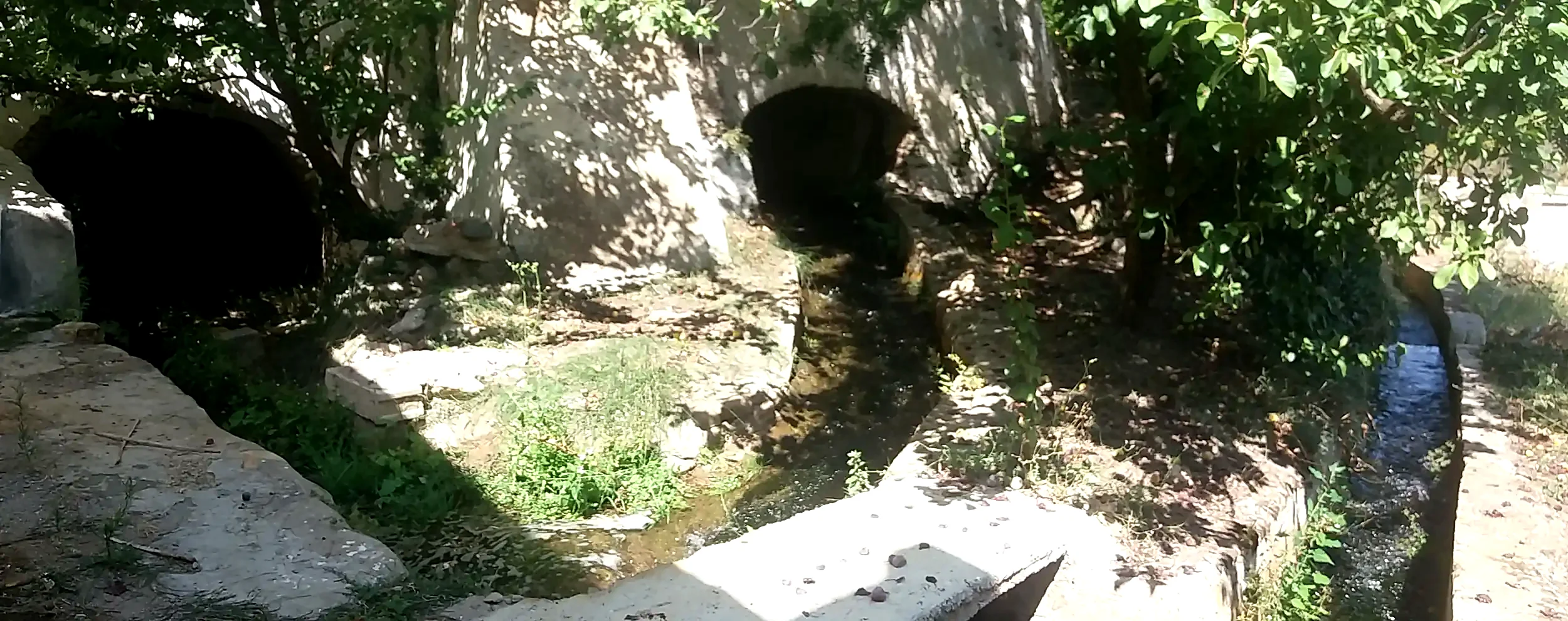 Canales de agua, arcos y vegetación junto a los restos exteriores de un molino
