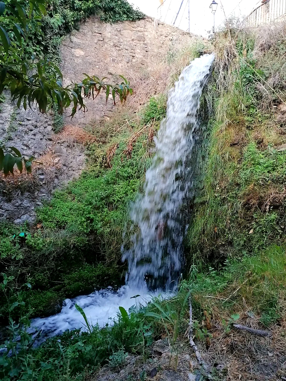 Salto de agua entre muros y vegetación en el entorno del molino
